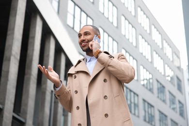 Photo of Happy man talking on smartphone outdoors. Lawyer, businessman, accountant or manager