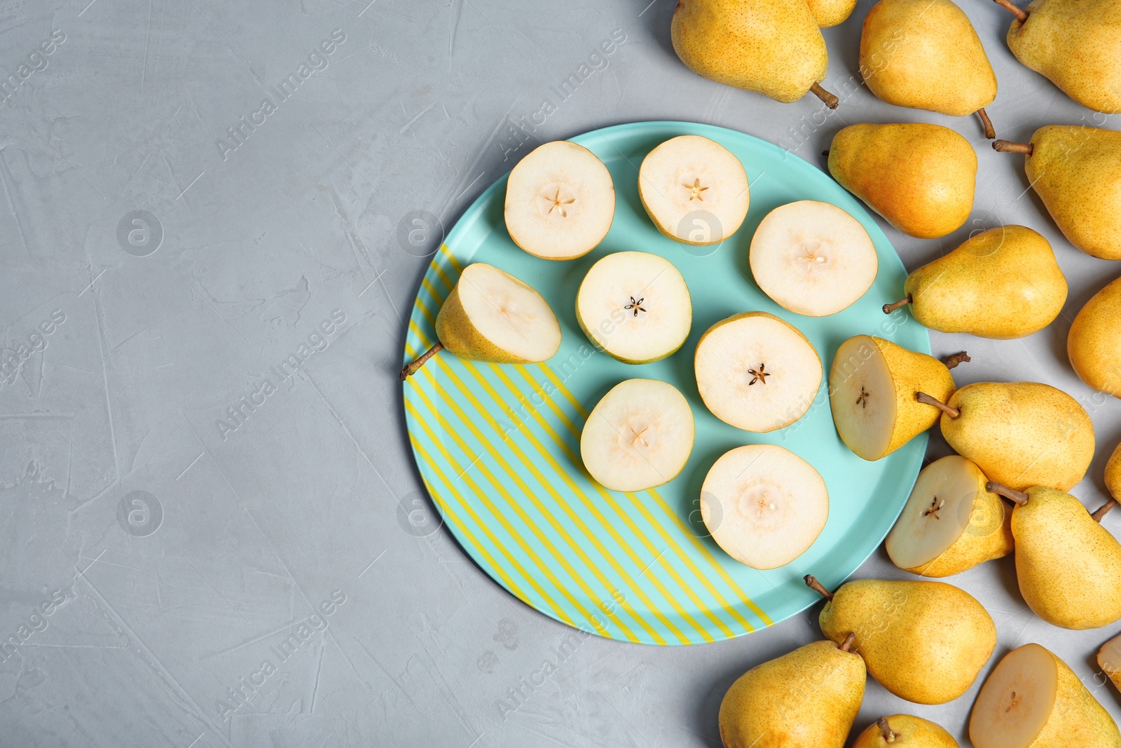 Photo of Flat lay composition with fresh ripe pears and tray on gray background. Space for text