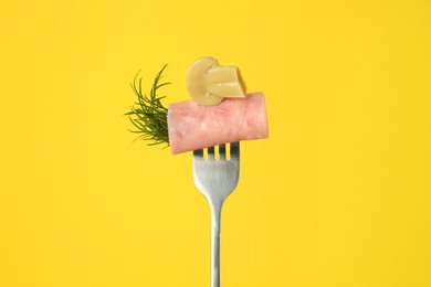 Photo of Fork with tasty slice of ham, pickled mushroom and dill on yellow background