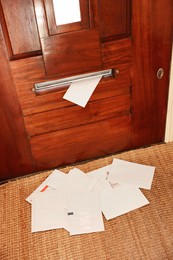 Photo of Wooden door with mail slot and many envelopes indoors, above view