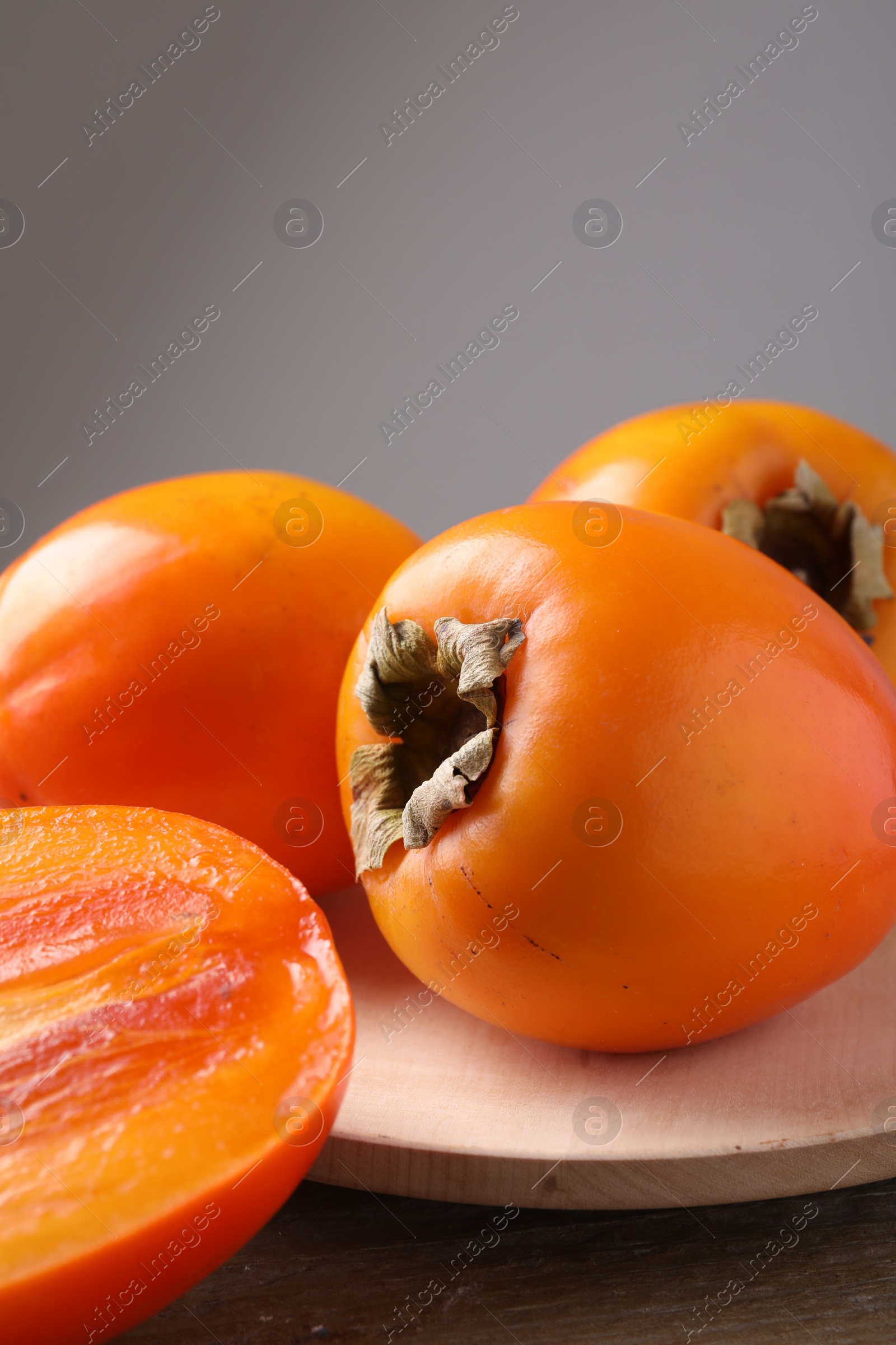 Photo of Whole and cut delicious ripe persimmons on wooden table