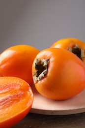 Photo of Whole and cut delicious ripe persimmons on wooden table