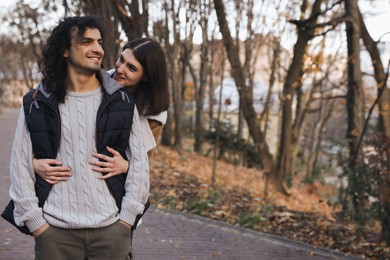 Happy young couple spending time together in autumn park, space for text. Dating agency