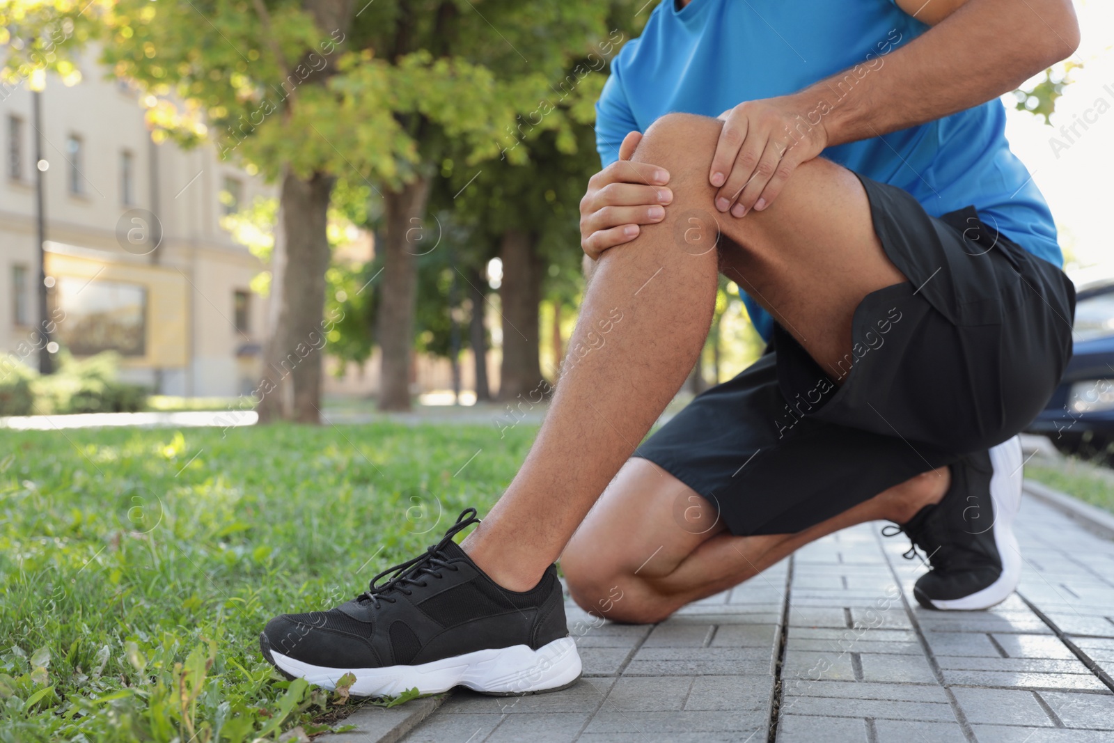 Photo of Man in sportswear having knee problems outdoors, closeup