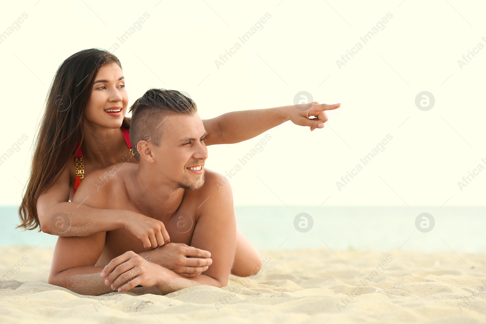 Photo of Young woman in bikini spending time with her boyfriend on beach. Lovely couple