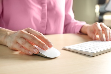 Photo of Woman using computer mouse and keyboard at table, closeup
