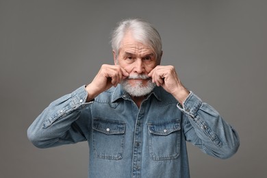 Photo of Senior man touching mustache on grey background