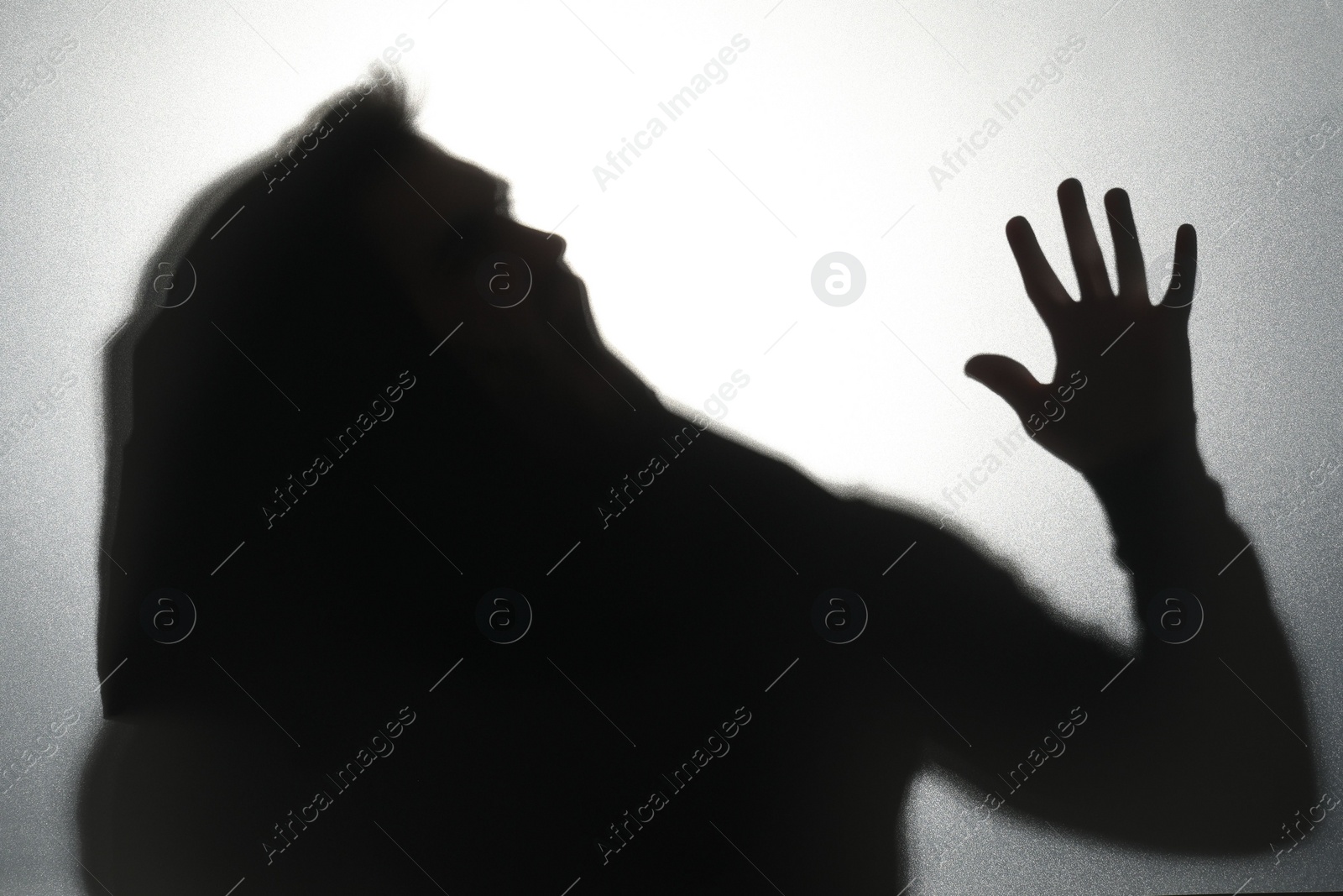 Photo of Silhouette of ghost behind glass against light grey background