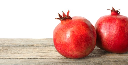 Fresh pomegranates on wooden table against white background, space for text