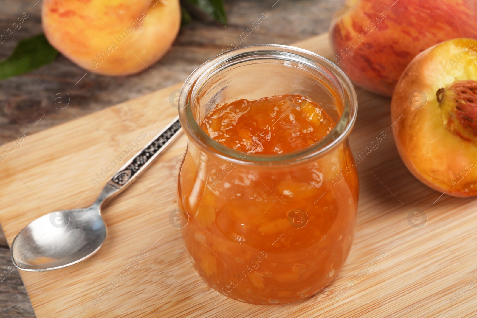 Photo of Jar with tasty peach jam on wooden table