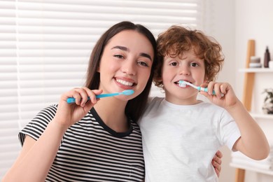 Mother and her son brushing teeth together in bathroom