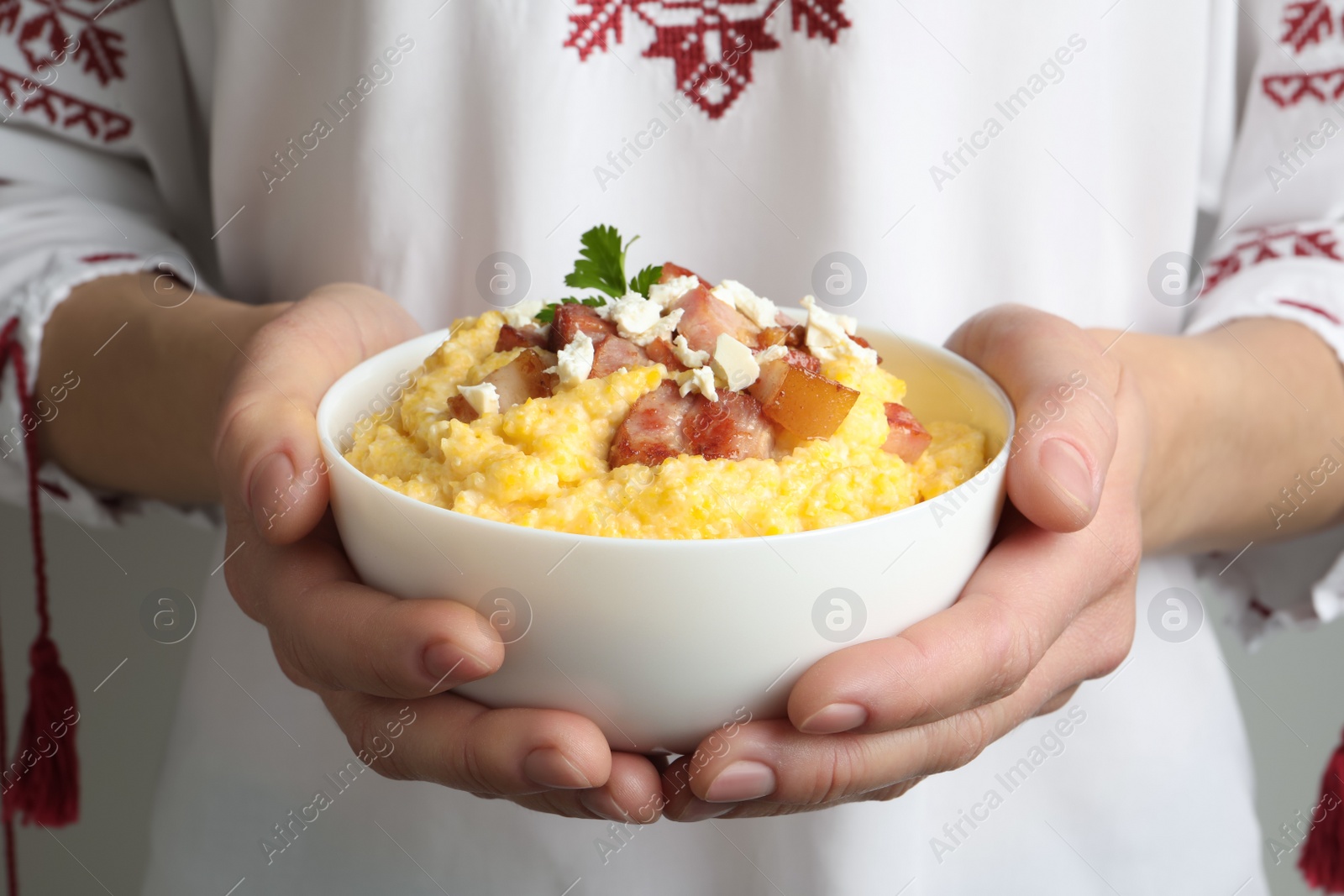 Photo of Woman holding bowl of delicious traditional Ukrainian banosh, closeup