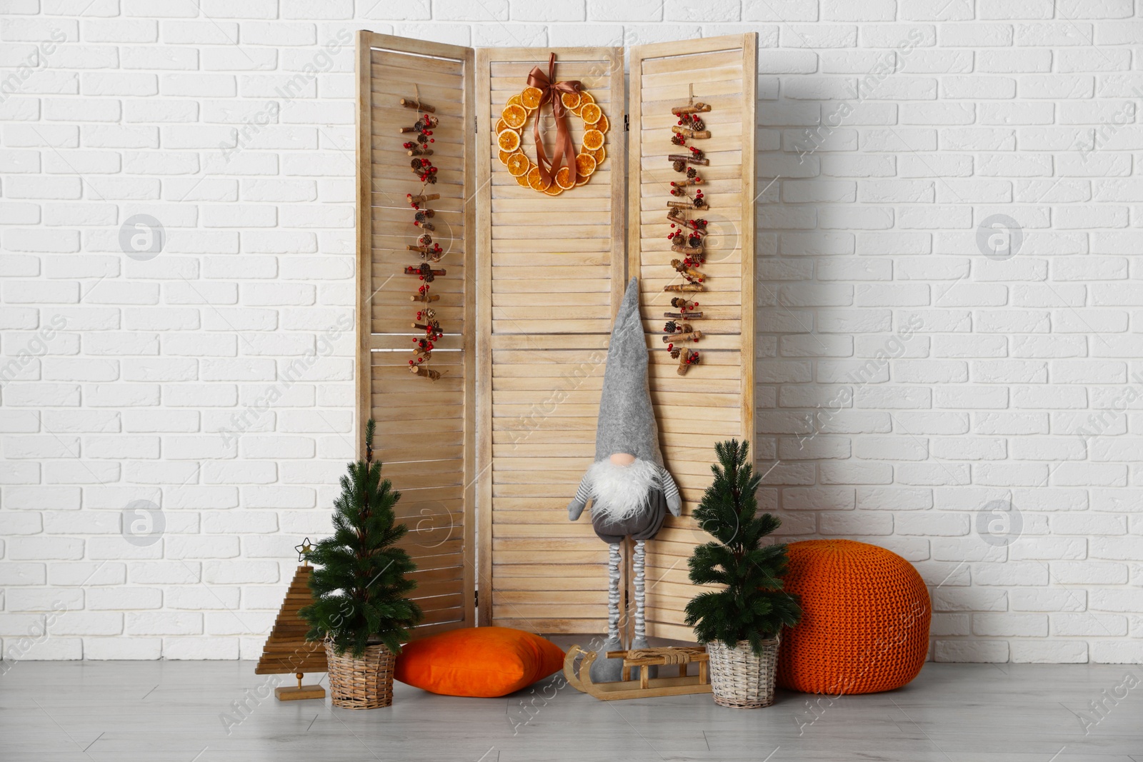 Photo of Beautiful Christmas themed photo zone with small trees, dwarf and fir decor near white brick wall