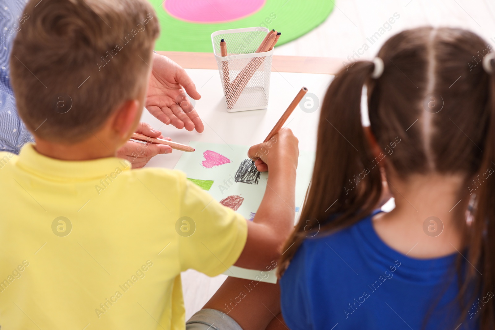 Photo of Little children drawing at desk, back view. Kindergarten activity