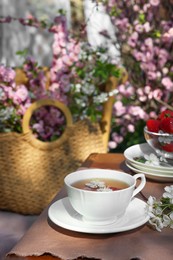 Photo of Beautiful spring flowers and ripe strawberries on table served for tea drinking in garden