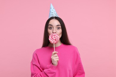 Photo of Woman in party hat holding lollipop on pink background