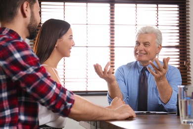 Senior notary working with young couple in office