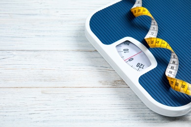 Photo of Scales, measuring tape and space for text on wooden background. Weight loss
