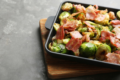 Photo of Delicious Brussels sprouts with bacon served on grey table, closeup