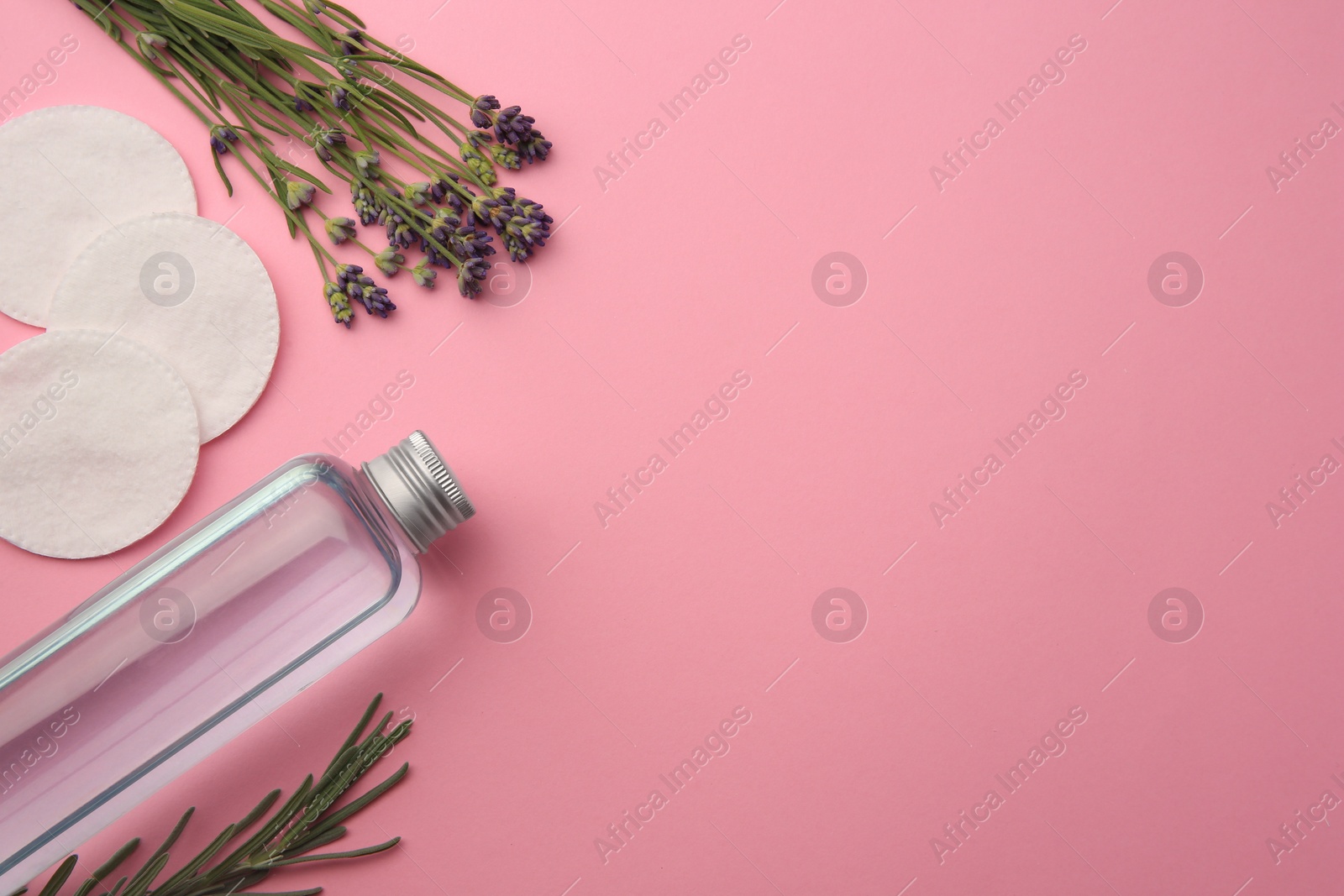 Photo of Flat lay composition with bottle of makeup remover and cotton pads on pink background. Space for text