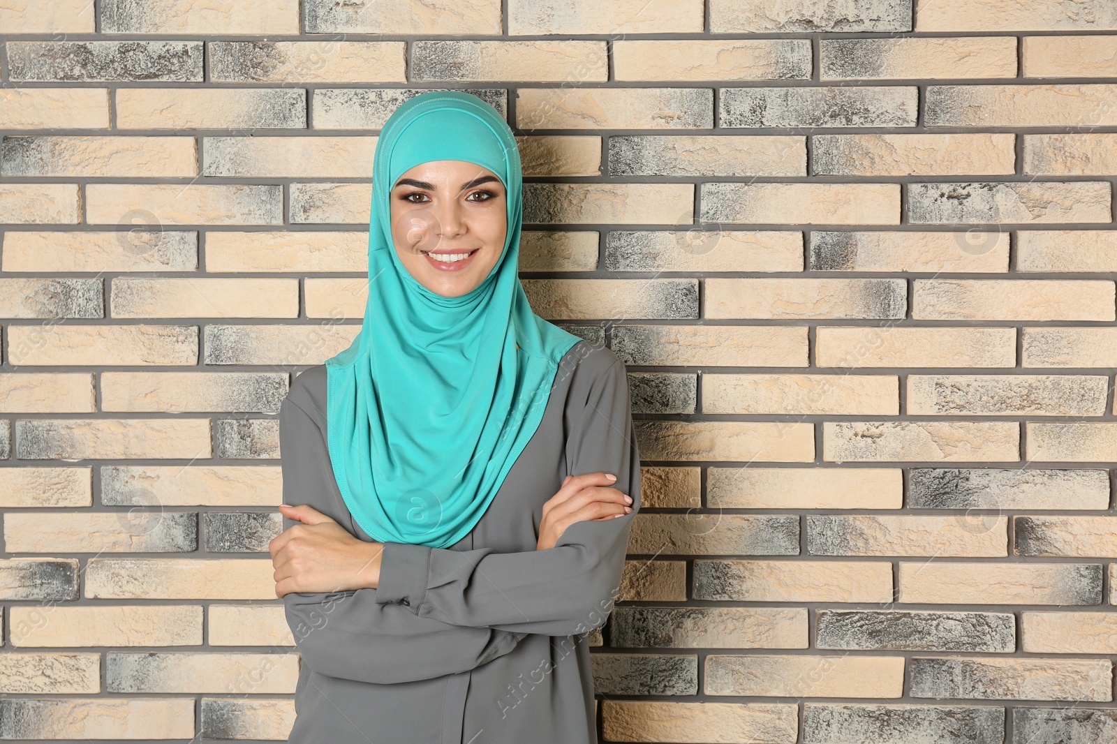 Photo of Portrait of young Muslim woman in hijab against brick wall