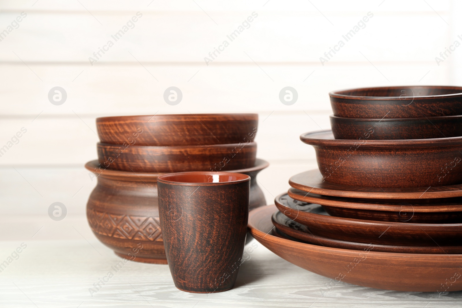 Photo of Set of clay utensils on white wooden table