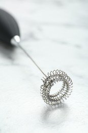 Photo of Black milk frother wand on white marble table, closeup