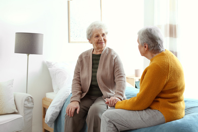 Elderly women spending time together in bedroom. Senior people care