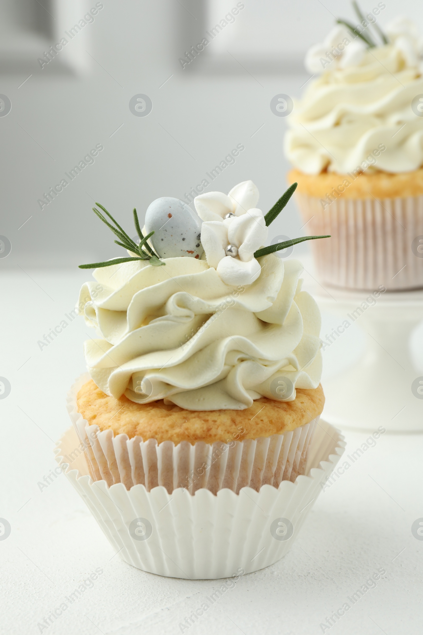 Photo of Tasty Easter cupcakes with vanilla cream on white table