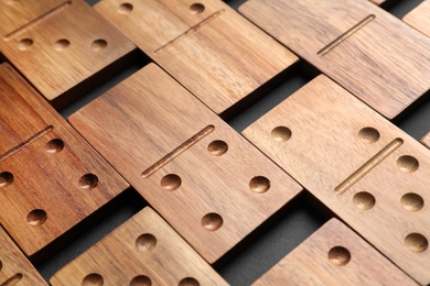 Photo of Set of wooden domino tiles on black background, closeup