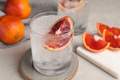 Delicious refreshing drink with sicilian orange and ice cubes on light table
