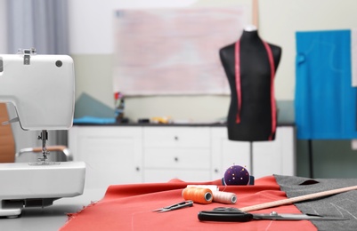 Photo of Fabric and sewing tools on table in tailor workshop