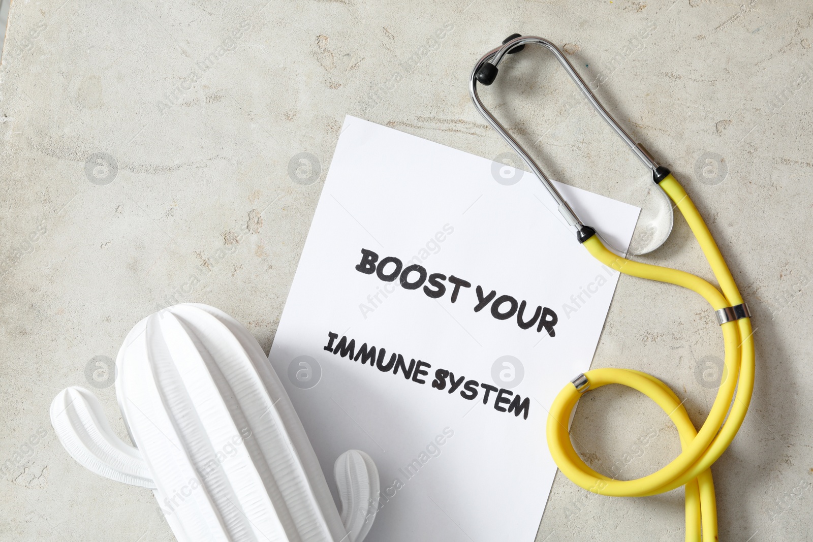 Photo of Sheet of paper with words Boost Your Immune System, stethoscope and ceramic cactus on light table, flat lay