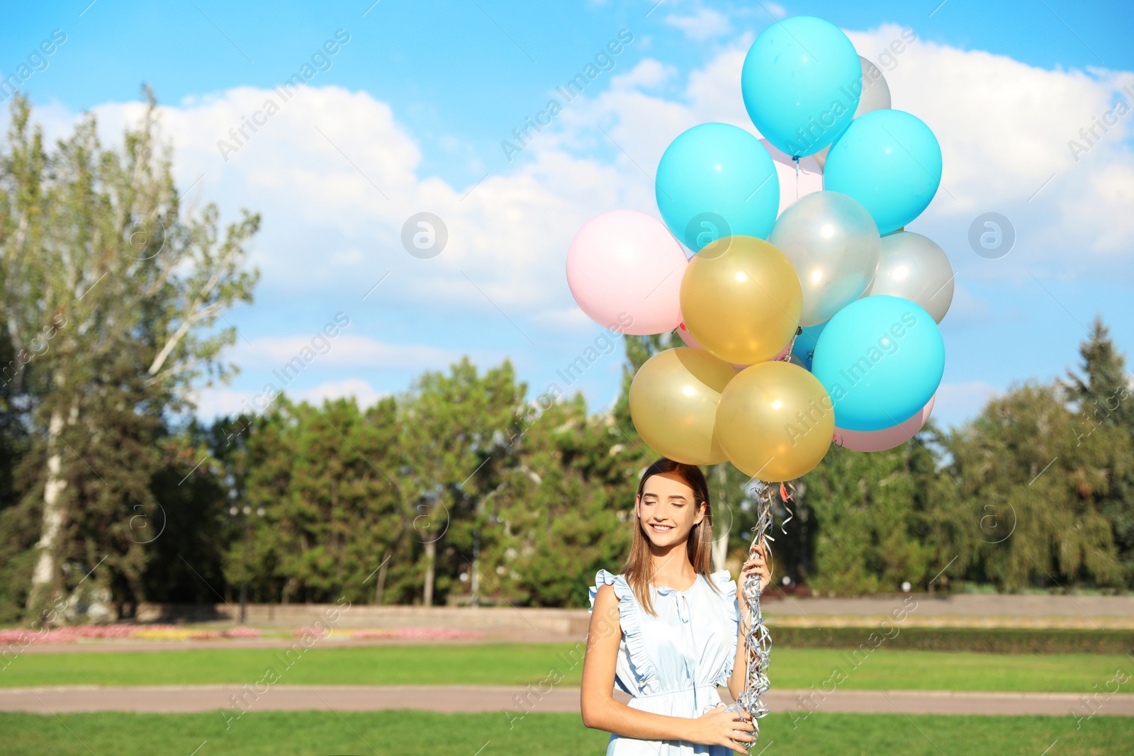 Photo of Beautiful teenage girl holding colorful balloons in park