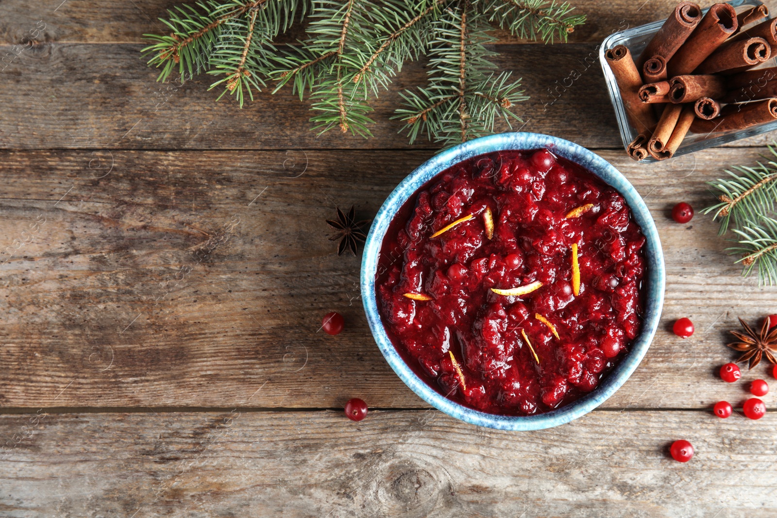 Photo of Flat lay composition with cranberry sauce in bowl on wooden background. Space for text
