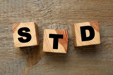 Photo of Abbreviation STD made with cubes on wooden table, flat lay