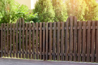 Photo of Wooden fence near beautiful trees on sunny day outdoors