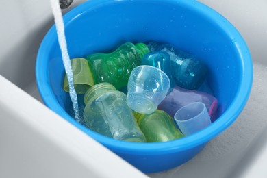 Light blue basin with baby bottles under stream of water in sink