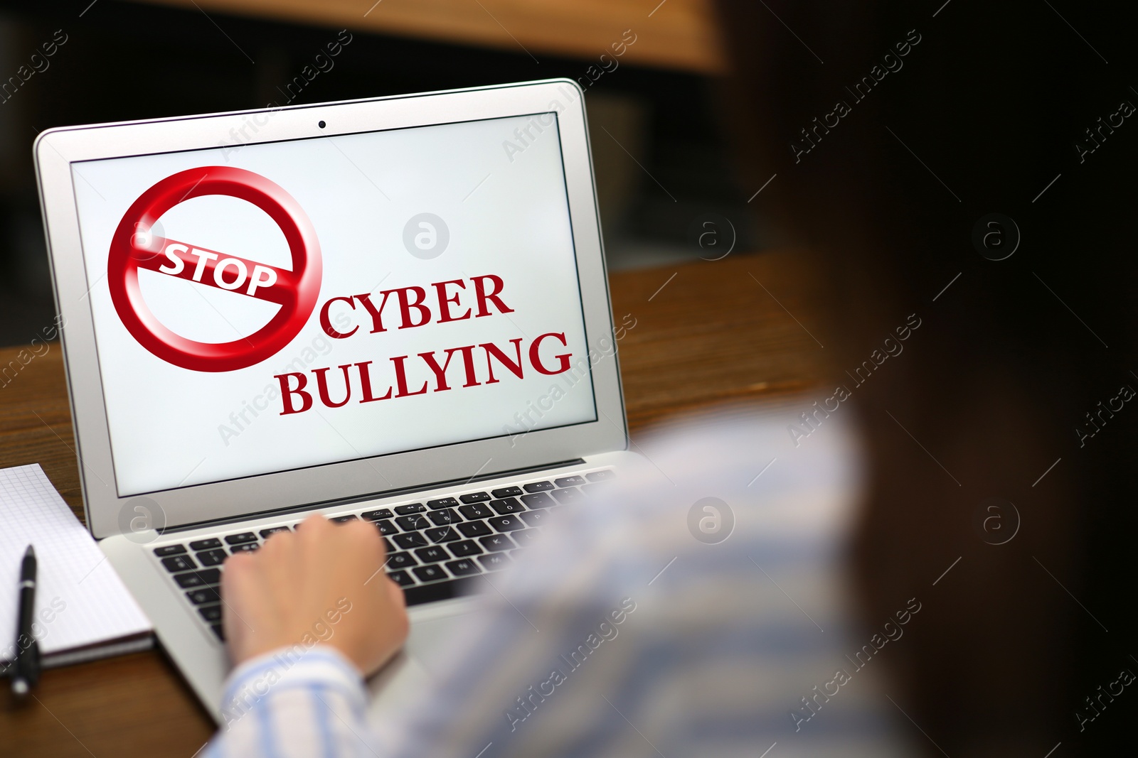 Image of Young woman using laptop at wooden table, closeup. Cyber bullying