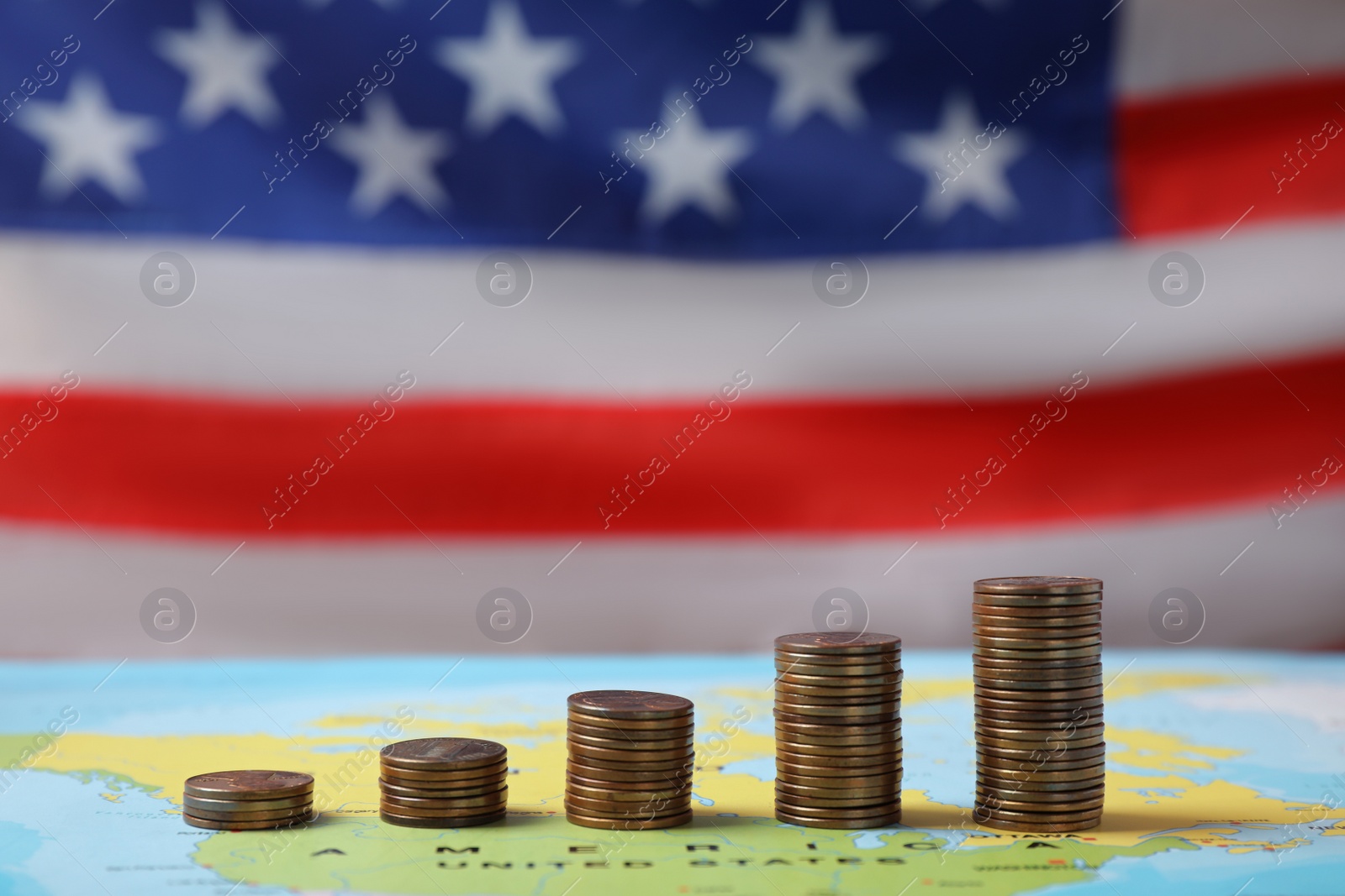 Photo of Stacks of USA cents on map against blurred flag