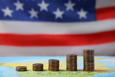 Stacks of USA cents on map against blurred flag