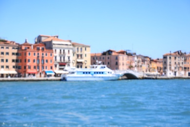 VENICE, ITALY - JUNE 13, 2019: Blurred view of city on sea shore and boat