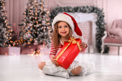 Photo of Cute little child with Christmas gift at home