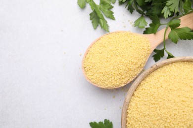 Photo of Raw couscous in bowl, spoon and parsley on light table, flat lay. Space for text