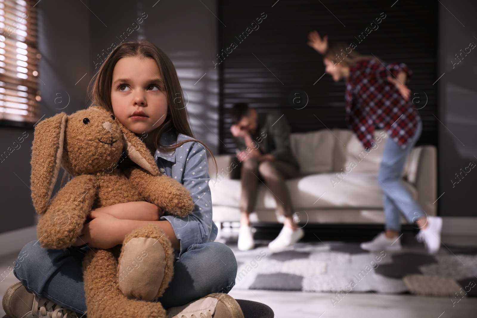 Photo of Couple fighting at home, focus on their unhappy little daughter. Domestic violence