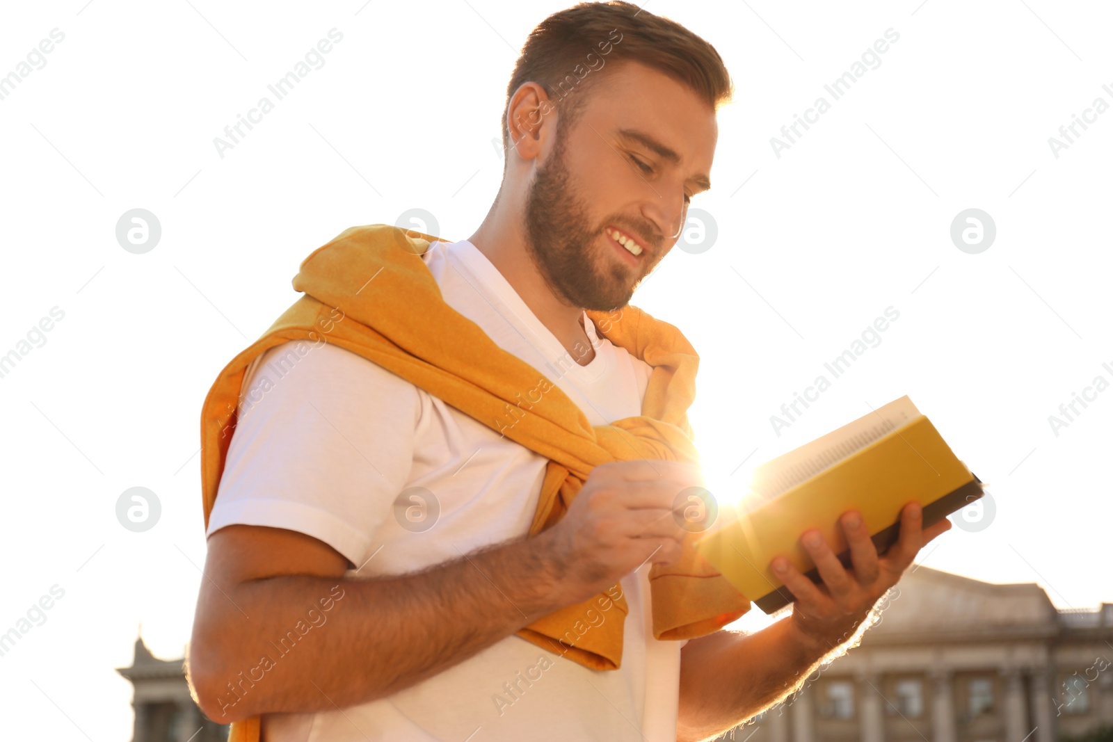 Photo of Young man reading book outdoors on sunny day