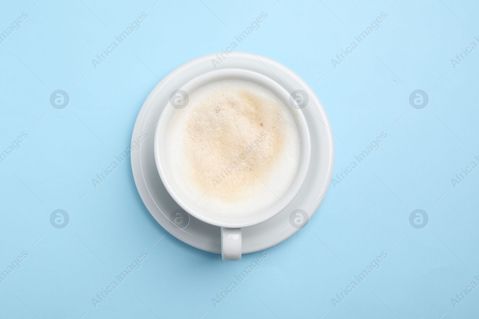 Photo of Aromatic coffee in cup on light blue background, top view