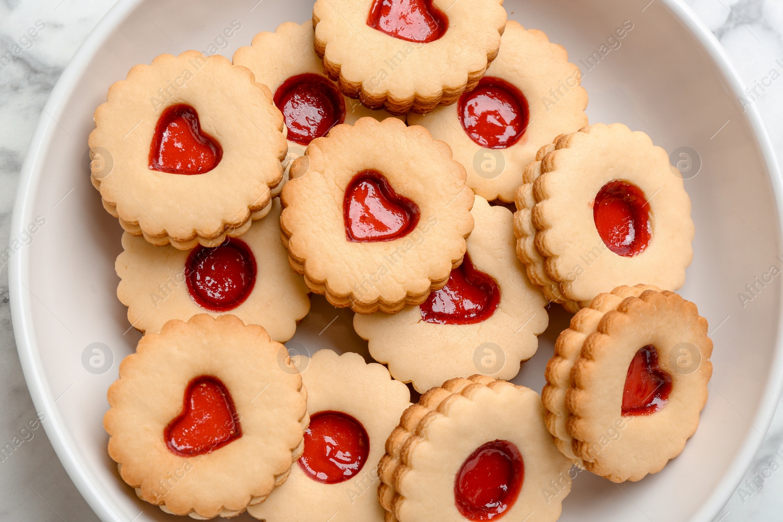 Photo of Traditional Christmas Linzer cookies with sweet jam on plate, top view