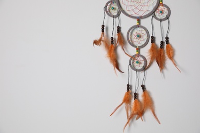 Photo of Beautiful dream catcher hanging on white wall. Space for text