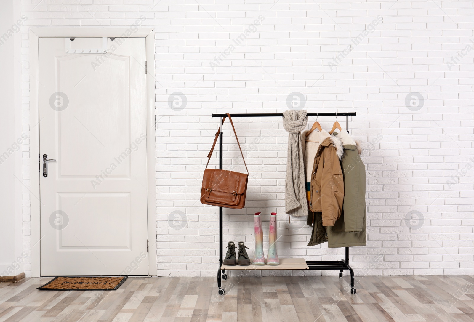 Photo of Stylish hallway interior with shoes and clothes on hanger stand